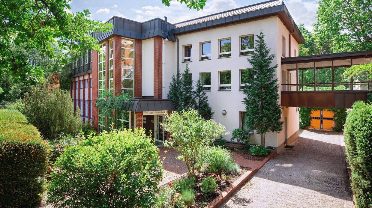 Außenansicht vom Hotel Morgenland, Haupteingang es ist sehr grün, die Sonne scheint, , ein paar Wolken sind zusehen 2018