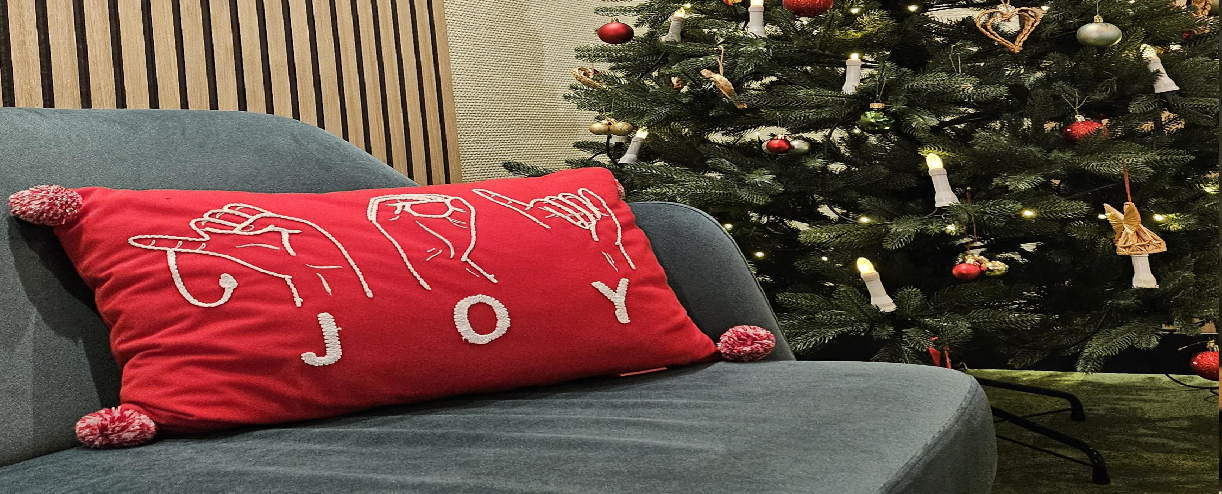 Couch in der Lobby mit einem roten Kissen, rechts daneben eine Weihnachtsbaum, ein Weihnachtsbaum mit Lichter, Kugeln, Holzanhänger